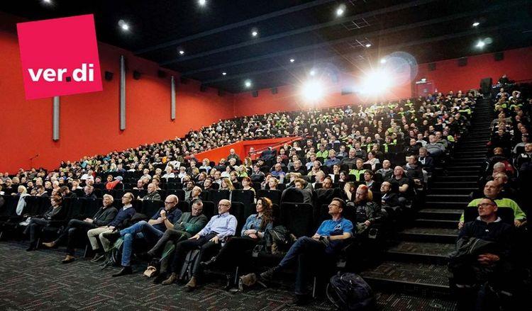 Menschen im Kino mit ver.di-Logo, Einstiegsgehalt für Zusteller:innen